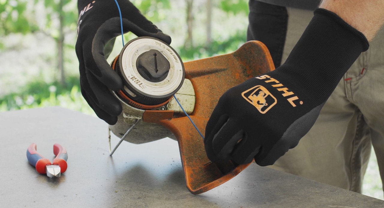 Person winding mowing line into a STIHL FSA 57 cordless brushcutter 